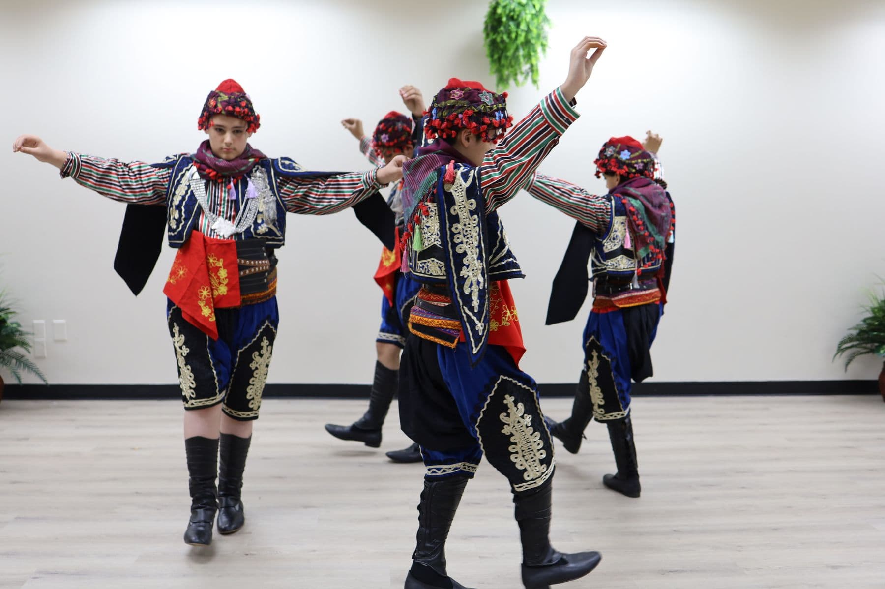 Three boys in folk costume rehearse a dance